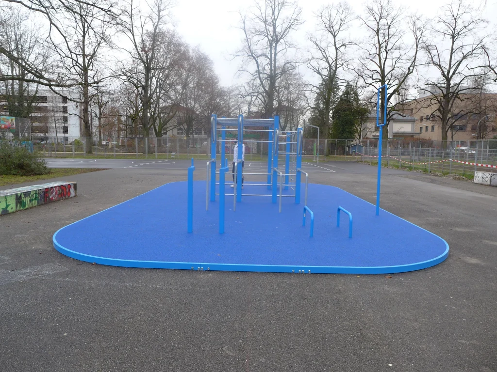 Street-Workout-Anlage im Horburgpark mit blauem Fallschutzbelag und Trainingsgeräten in der Gesamtansicht.